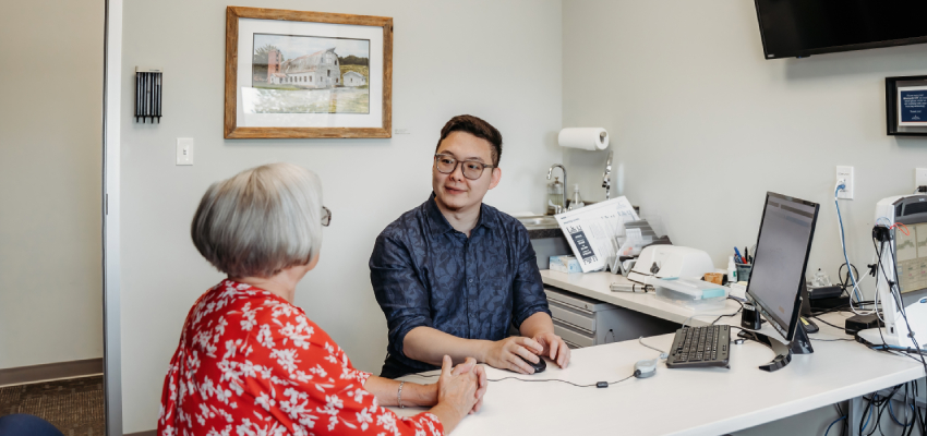 An audiologist consulting with a patient about the six realistic challenges and truths of hearing health care and hearing aid adoption