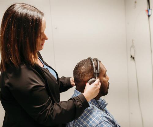 A middle-aged main receiving a hearing aid fitting from Audiologist Amy Longenecker